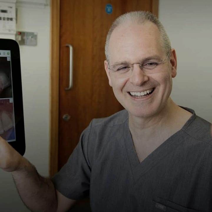 Dr Colin Houston smiling beside a digital dental scan